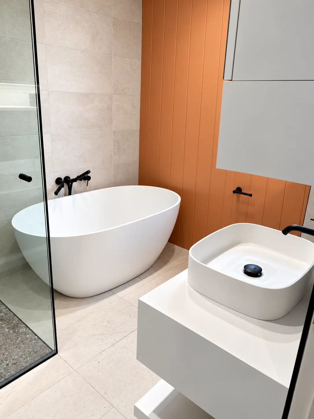 Contemporary bathroom with freestanding bath, vessel basin and terracotta feature wall